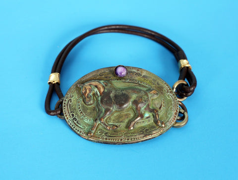 trotting horse on solid brass hand-cast oval with purple gemstone accent, on double leather cord with lobster clasp closure